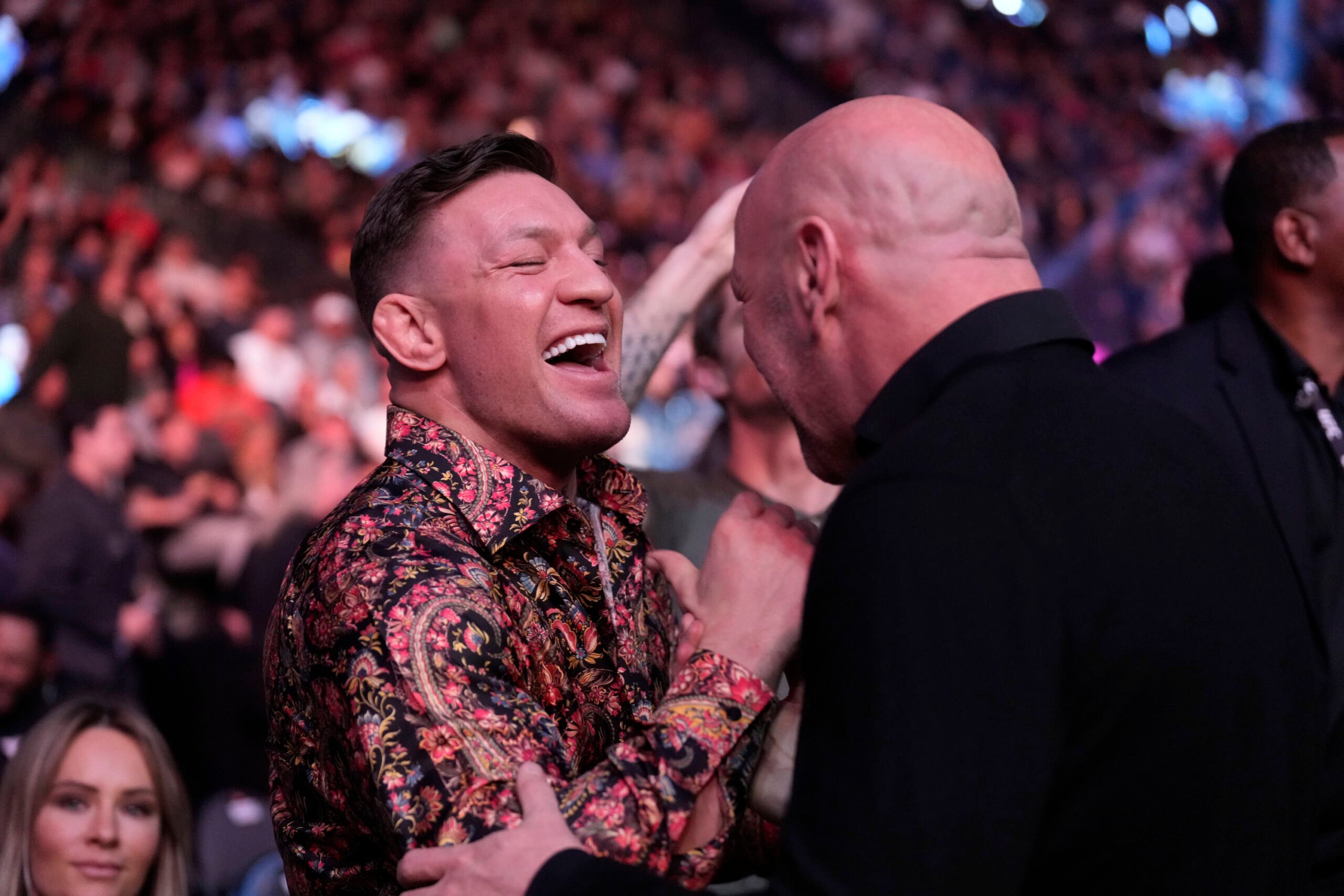 Conor McGregor in a designer shirt laughs with Dana White, who is only visible from the back