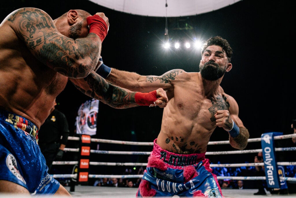 Mike Perry in pink and blue shorts throws a bunch at Thiago Alves