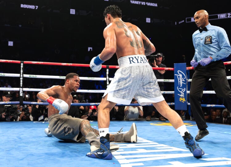 Ryan Garcia (white trunks) knocks down Devin Haney (gray trunks) during their WBC Super Lightweight title bout at Barclays Center on April 20, 2024...