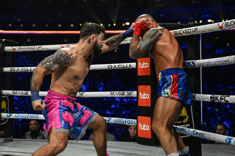 Mike Perry in pink shorts punches Thiago Alves in blue and red inside a boxing ring with white ropes and red ring posts