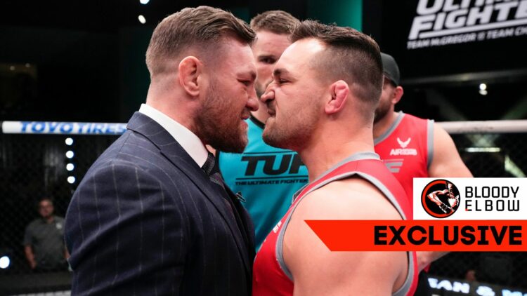 Conor McGregor in a suit facing off with Michael Chandler in a red sleeveless shirt. There is an overlay noting that this story is a Bloody Elbow E...