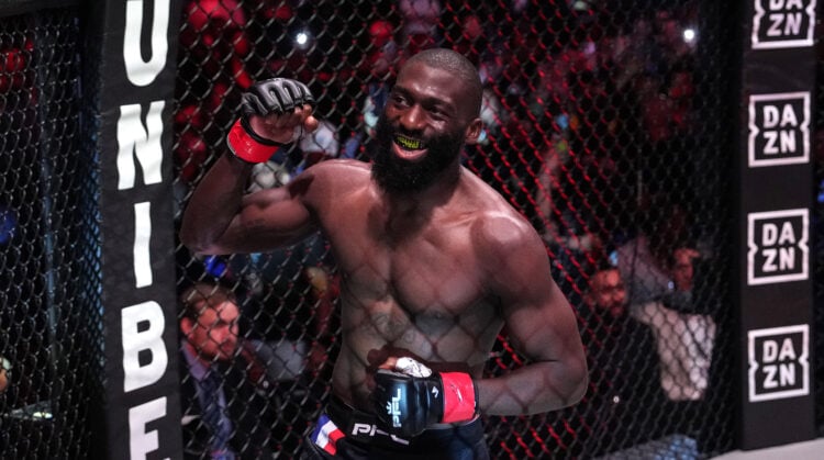 Cedric Doumbe with his fist in the air celebrating a win inside a PFL MMA cage