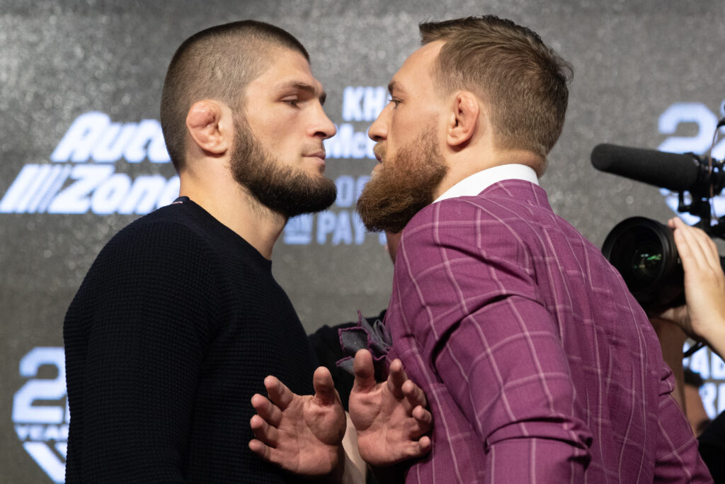 Khabib Nurmagomedov in all black and Conor McGregor in a pink suit facing off
