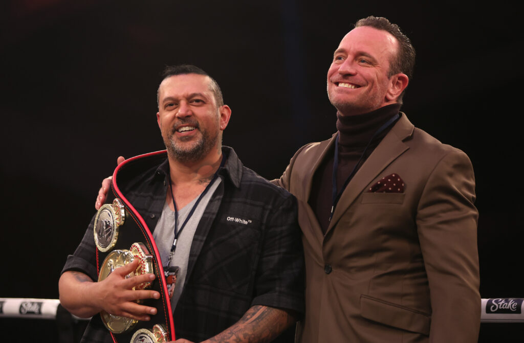 Mams Taylor holding a Misfits Boxing belt laughs with Kalle Sauerland inside a Boxing ring