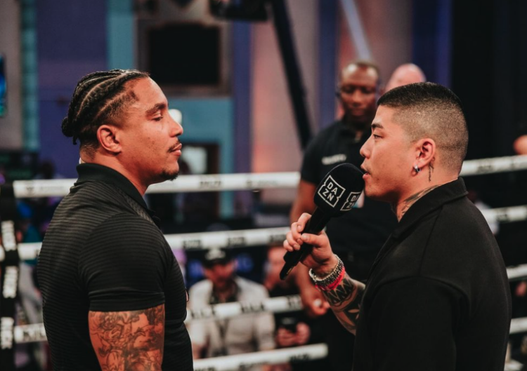 Anthony Taylor stares down Samuel Ericsson, who holds a DAZN microphone in a boxing ring