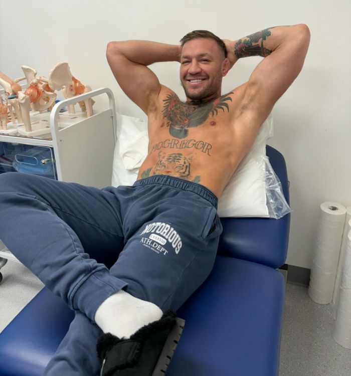 Conor McGregor smiling as he sits on a doctor's bed