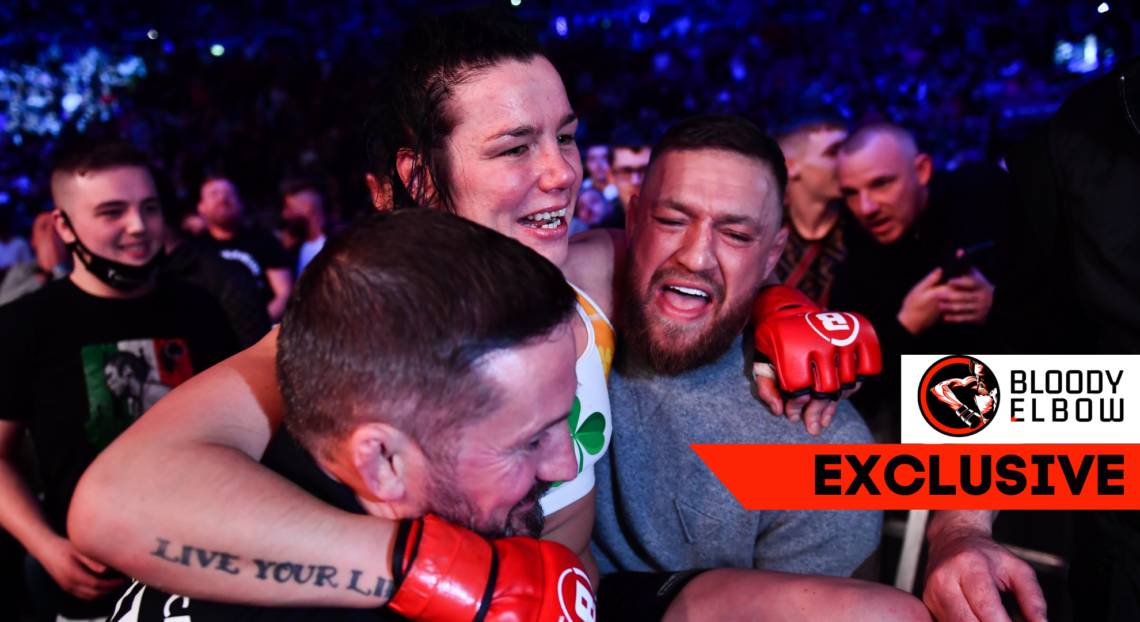 Photo shows John Kavanagh and Conor McGregor carrying Sinead Kavanagh outside of the Bellator cage