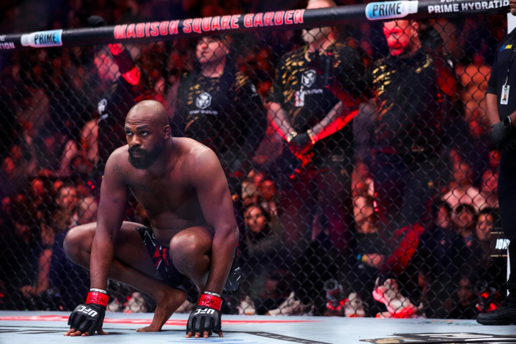 Jon Jones kneels in the cage before UFC 309