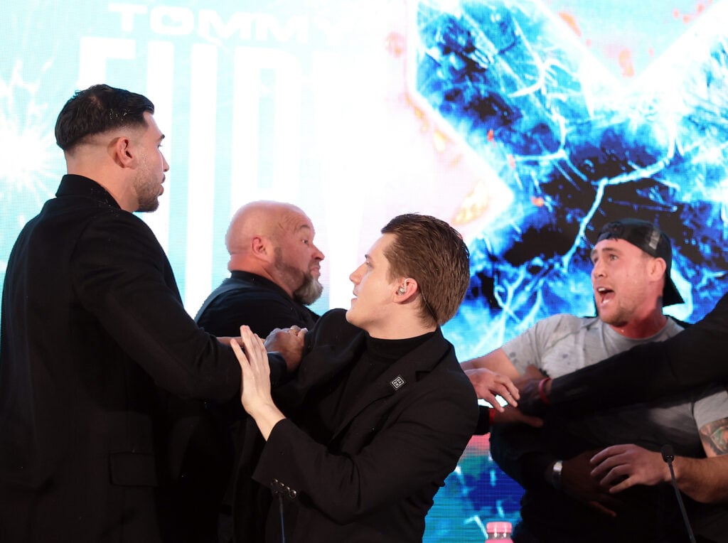 Tommy Fury and Darren Till are held apart by security and Ben Davis during press conference