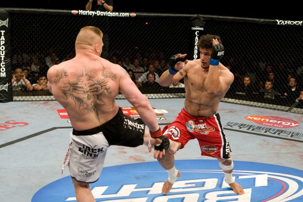 Brock Lesnar lands a kick on Frank Mir during UFC 100