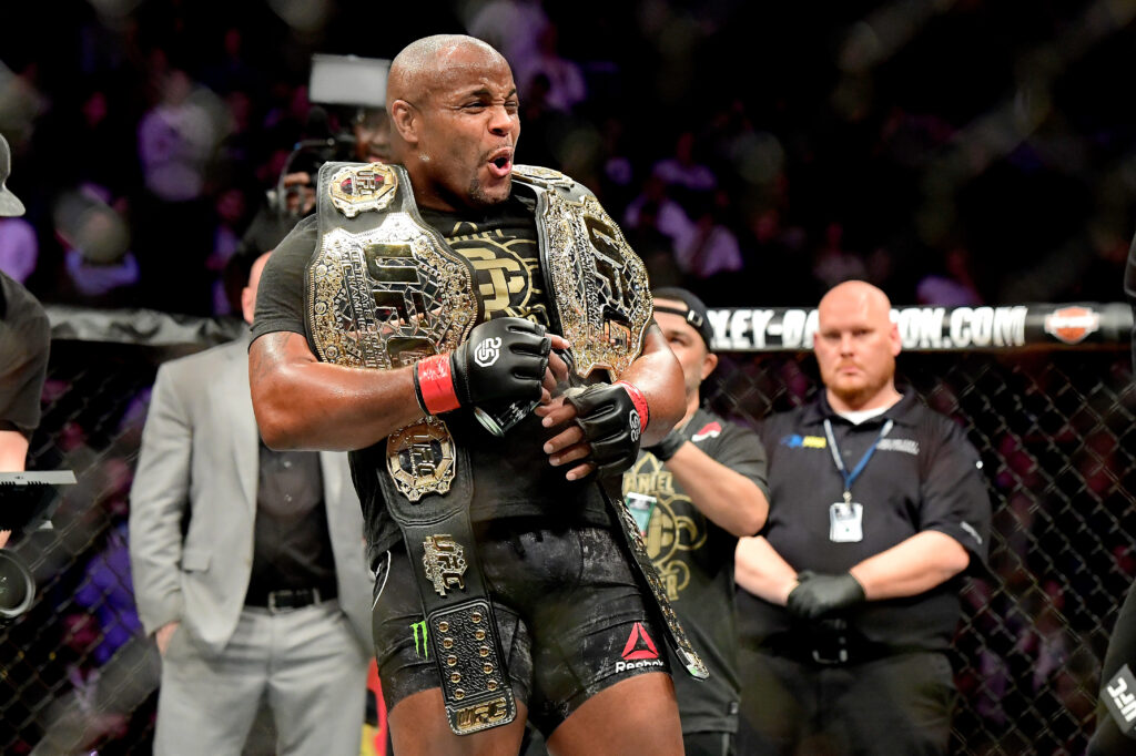 Daniel Cormier celebrates with two UFC titles after beating Derrick Lewis at UFC 230