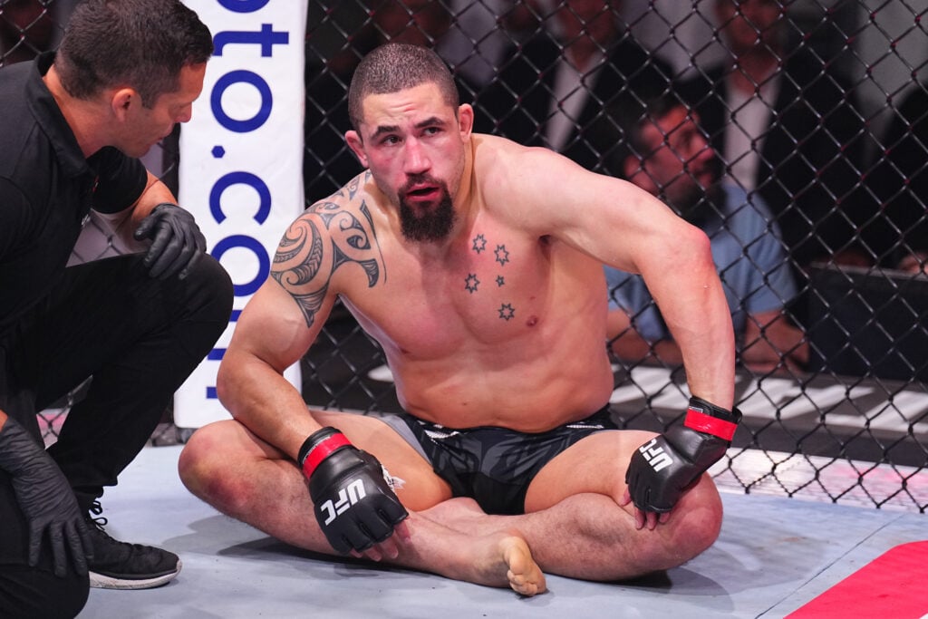 Robert Whittaker sits crossed legged in the octagon after a submission loss to Khamzat Chimaev