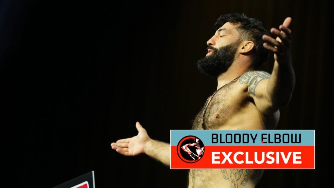 Roman Dolidze of Georgia poses on the scale during the UFC 307 ceremonial weigh-in at Salt Palace Convention Center. Overlaid, the Bloody Elbow Exc...