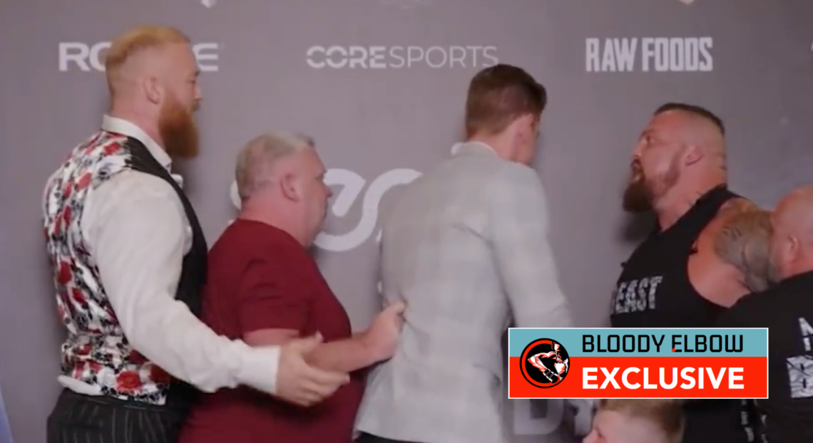 Eddie Hall and Thor Bjornsson being separated during their pre-fight press conference. Overlay text reads: BLOODY ELBOW EXCLUSIVE