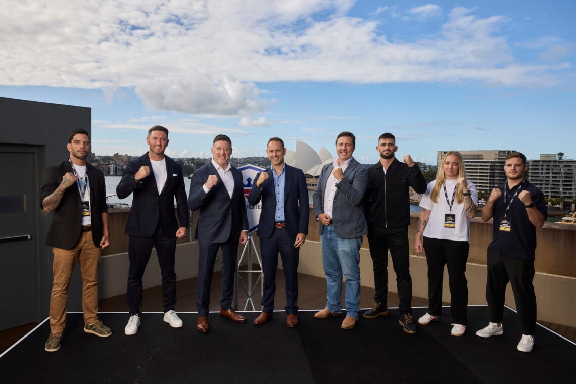 A group of PFL Executives and fighters pose with their fists up in front of the Sydney Opera house.
