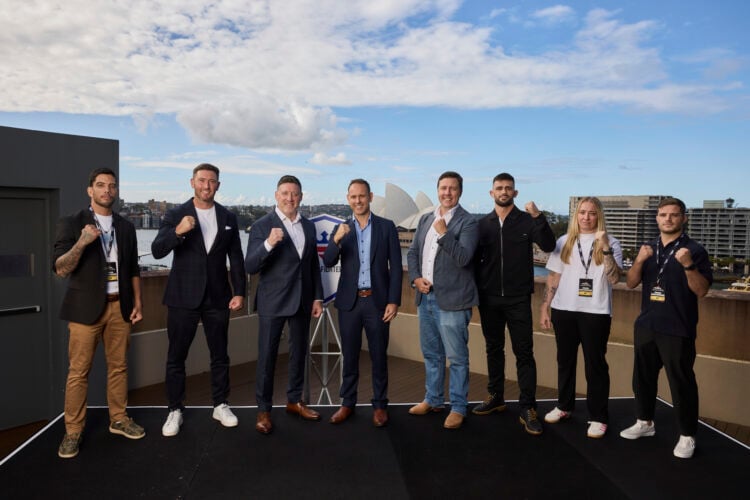 A group of PFL Executives and fighters pose with their fists up in front of the Sydney Opera house.