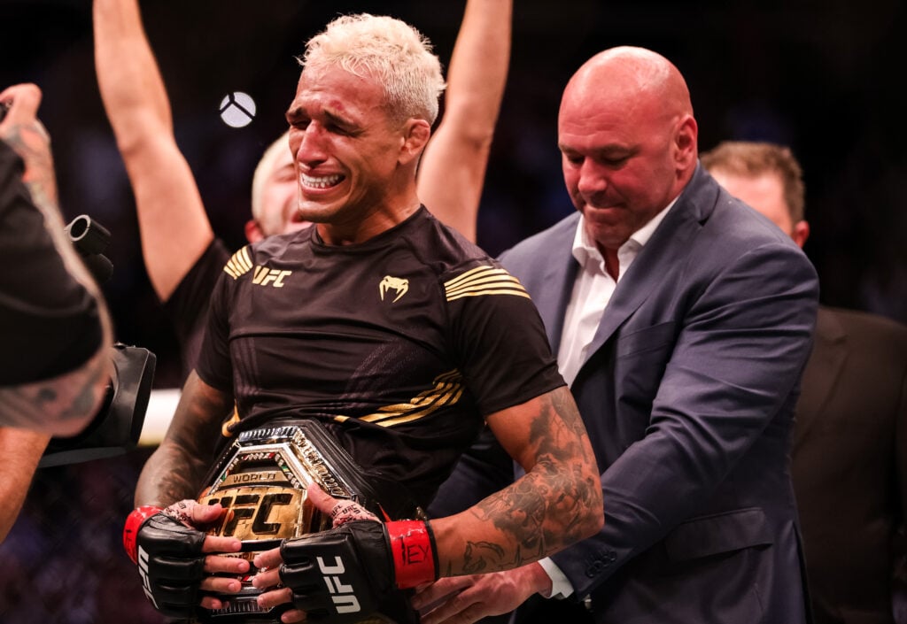Charles Oliveira reacts as Dana White puts the belt around his waist at UFC 262