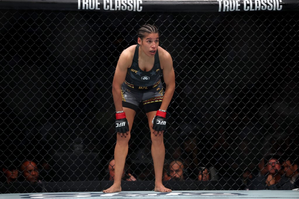 Julianna Pena leans back on the cage during her fight at UFC 316