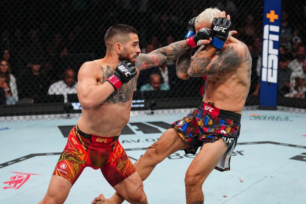 Ilia Topuria punches Charles Oliveira during their title fight at UFC 317.
