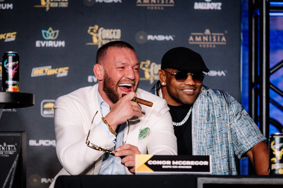 Conor McGregor holding a cigar alongside Yoel Romero