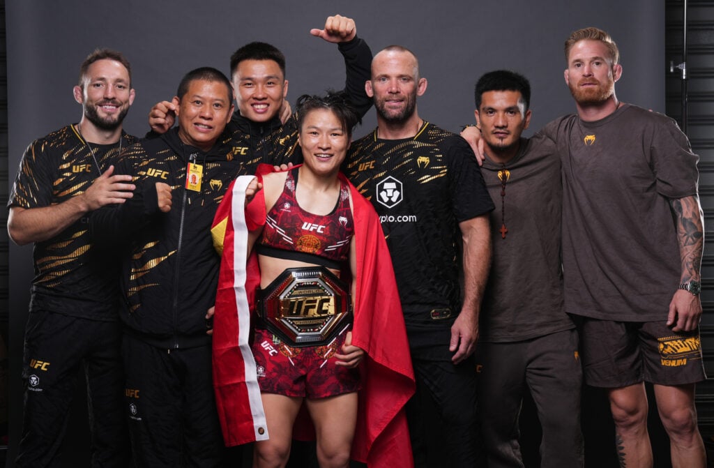 Zhang Weili poses with her team after defeating Tatiana Suarez in their title fight at UFC 312.