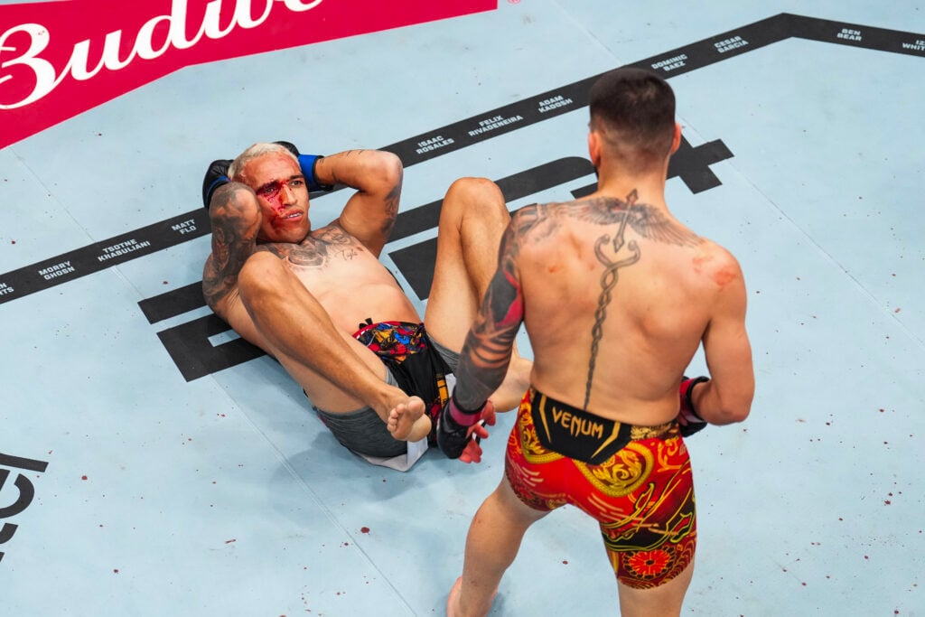 Charles Oliveira staring up at Ilia Topuria at UFC 317