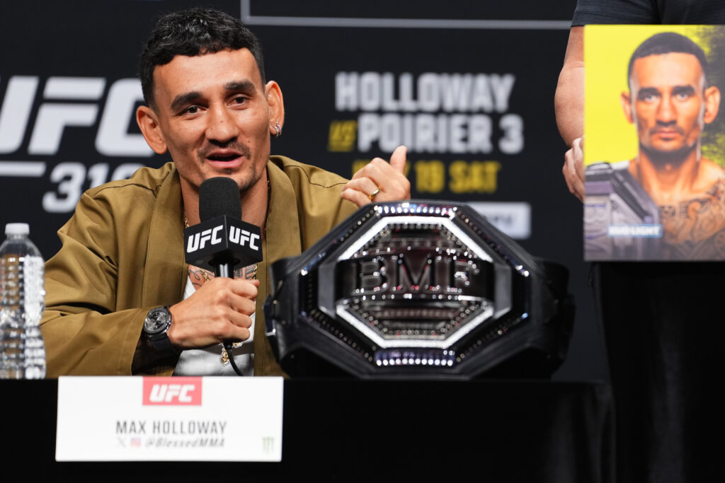 Max Holloway speaks on stage alongside his BMF title at the UFC 318 press conference.