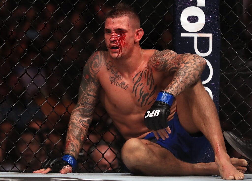 Dustin Poirier sits against the cage after suffering an illegal knee against Eddie Alvarez