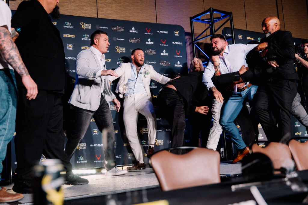 Conor McGreogr watches on as security hold back an angry Mike Perry.