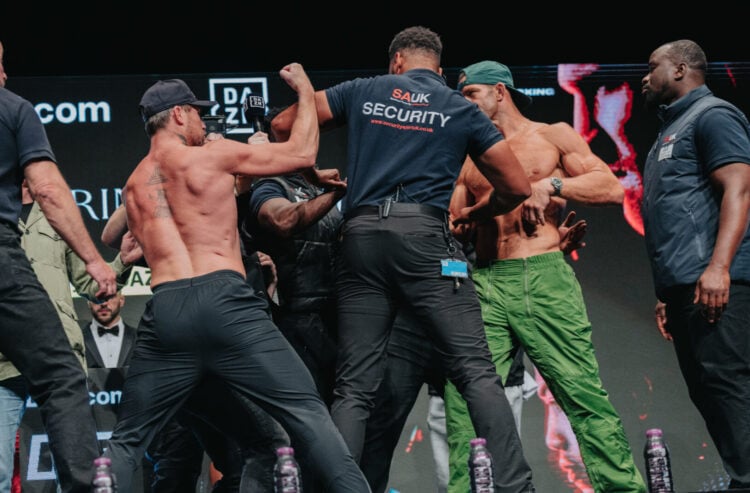 Darren Till and Luke Rockhold, both shirtless, are held back by security guards on stage