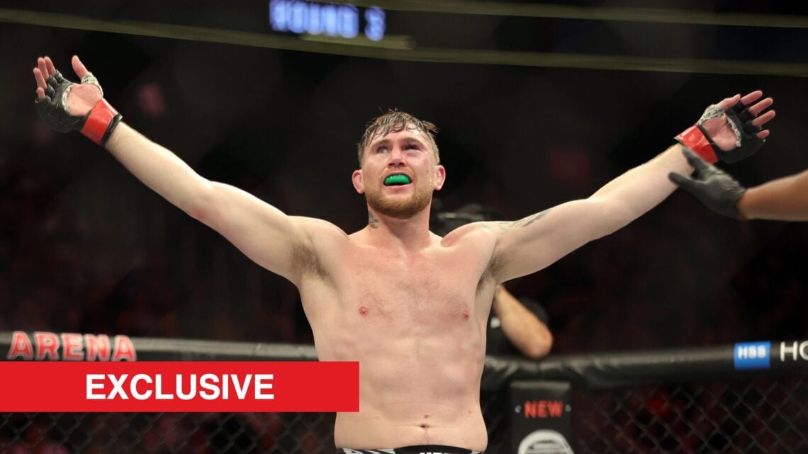 Darren Till raises his arms in the octagon during a fight
