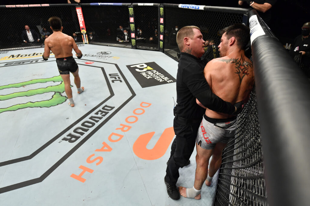Dominick Cruz protests the stoppage of his fight with Henry Cejudo to Keith Peterson