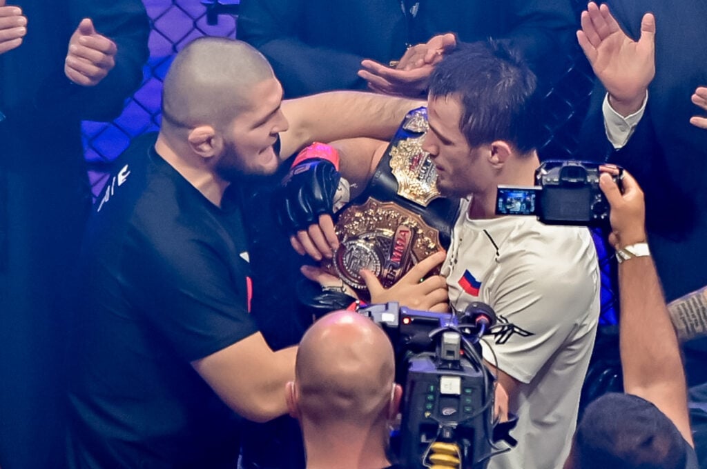 Khabib Nurmagomedov talks to Usman Nurmagomedov as he holds his belt in the cage after a PFL fight