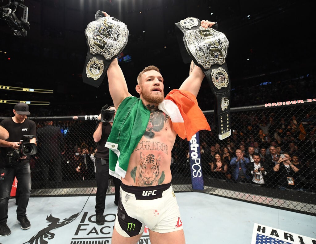 Conor McGregor celebrates with both belts at UFC 205