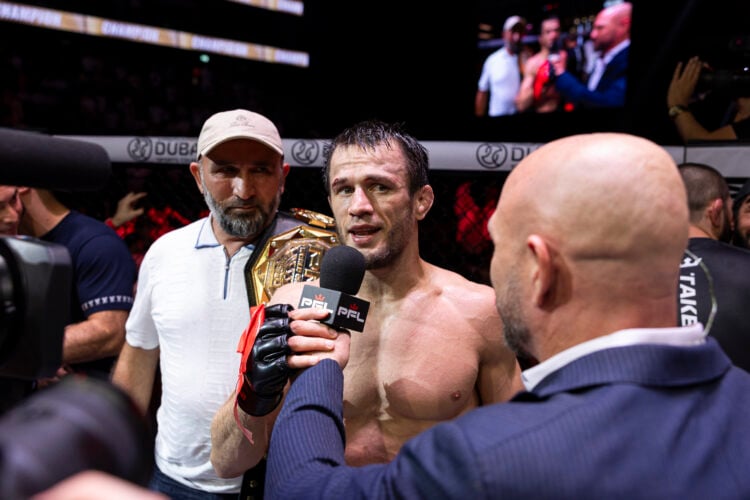 Usman Nurmagomedov speaks to the crowd after a win as his father watches on holding his PFL belt