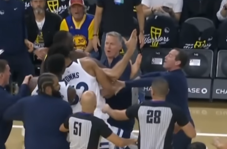 NBA player Rudy Gobert raises an arm in exasperation as Draymond Green puts him in a chokehold.