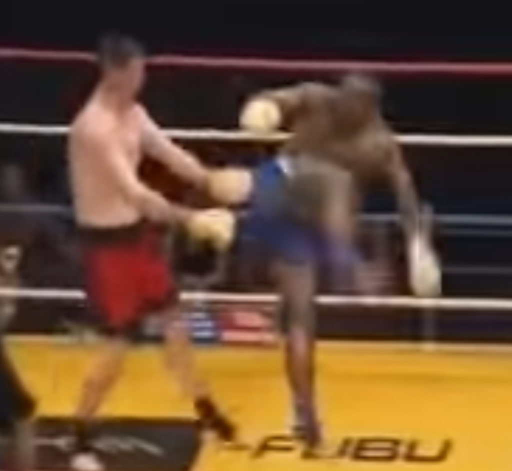 Kickboxer Stanley Nandex turns and begins to jump for a spinning heel kick to his opponent's head in a match.