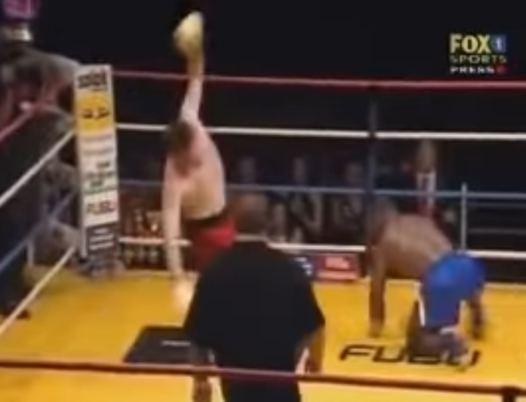 Kickboxer Stanley Nandex lands a kick against his opponent, who bounces off the ropes flailing. 